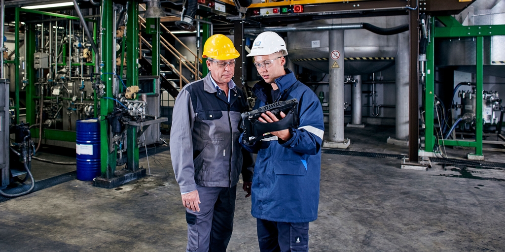 Nhân viên Endress+Hauser cùng với khách hàng trong nhà máy hóa chất nông nghiệp sử dụng thiết bị kỹ thuật số hỗ trợ field xpert